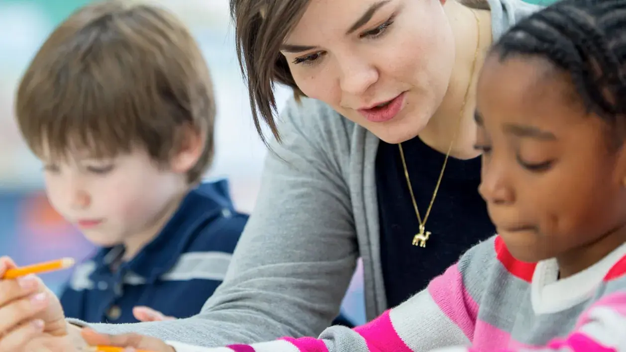 A teacher helping a student work on toolkit activities.
