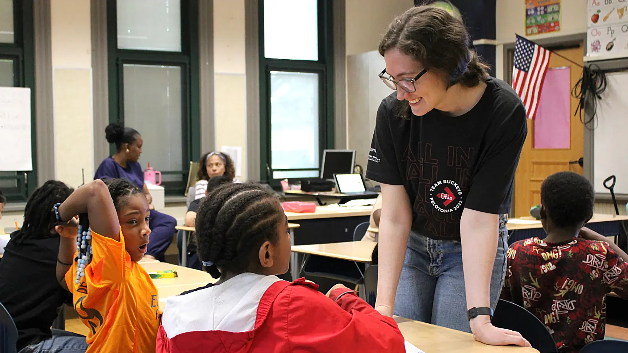 adult female working with a group of young students in a classroom setting