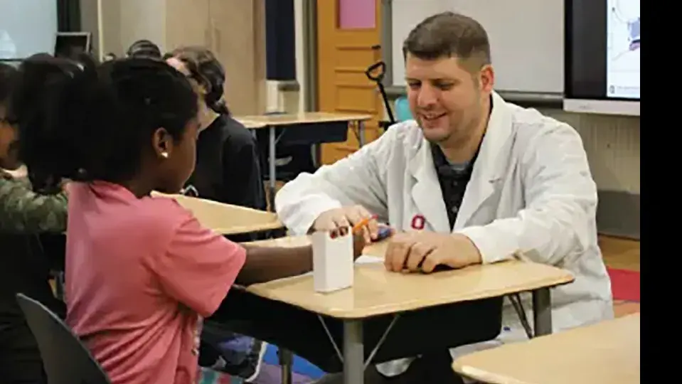 Generation Rx volunteer working with an elementary school student on an activity in a classroom.