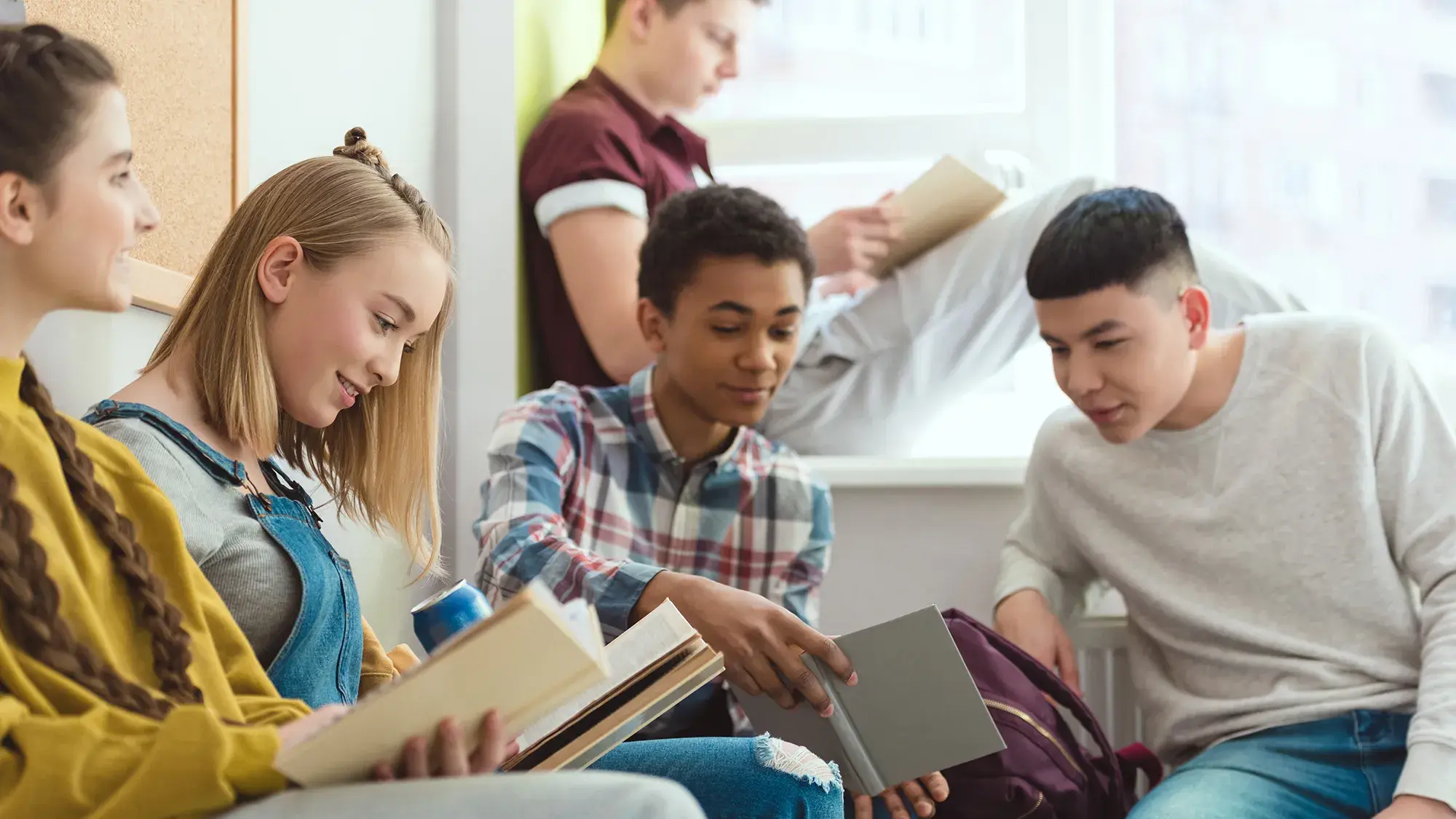 group of teens hanging out in a classroom reading books and sharing ideas
