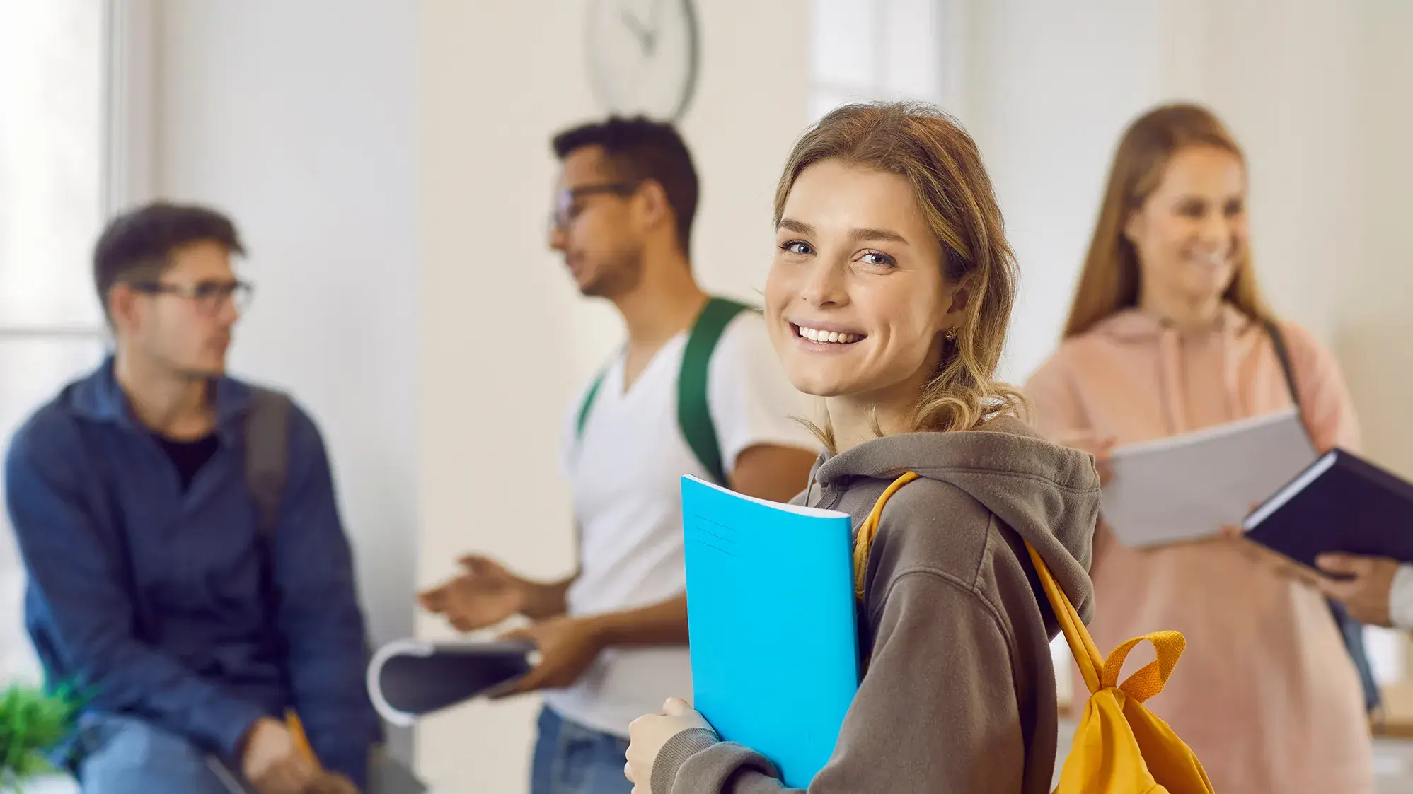 group of university students holding folders in a classroom setting