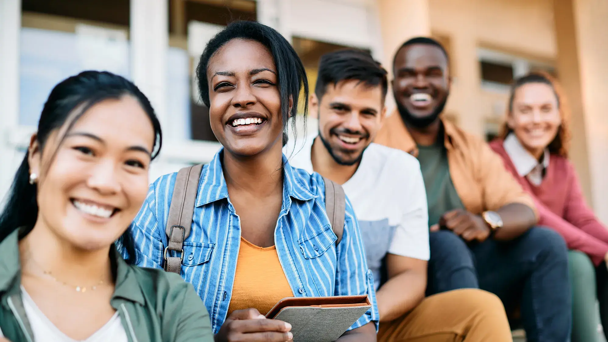 group of five young adults holding books and smiling