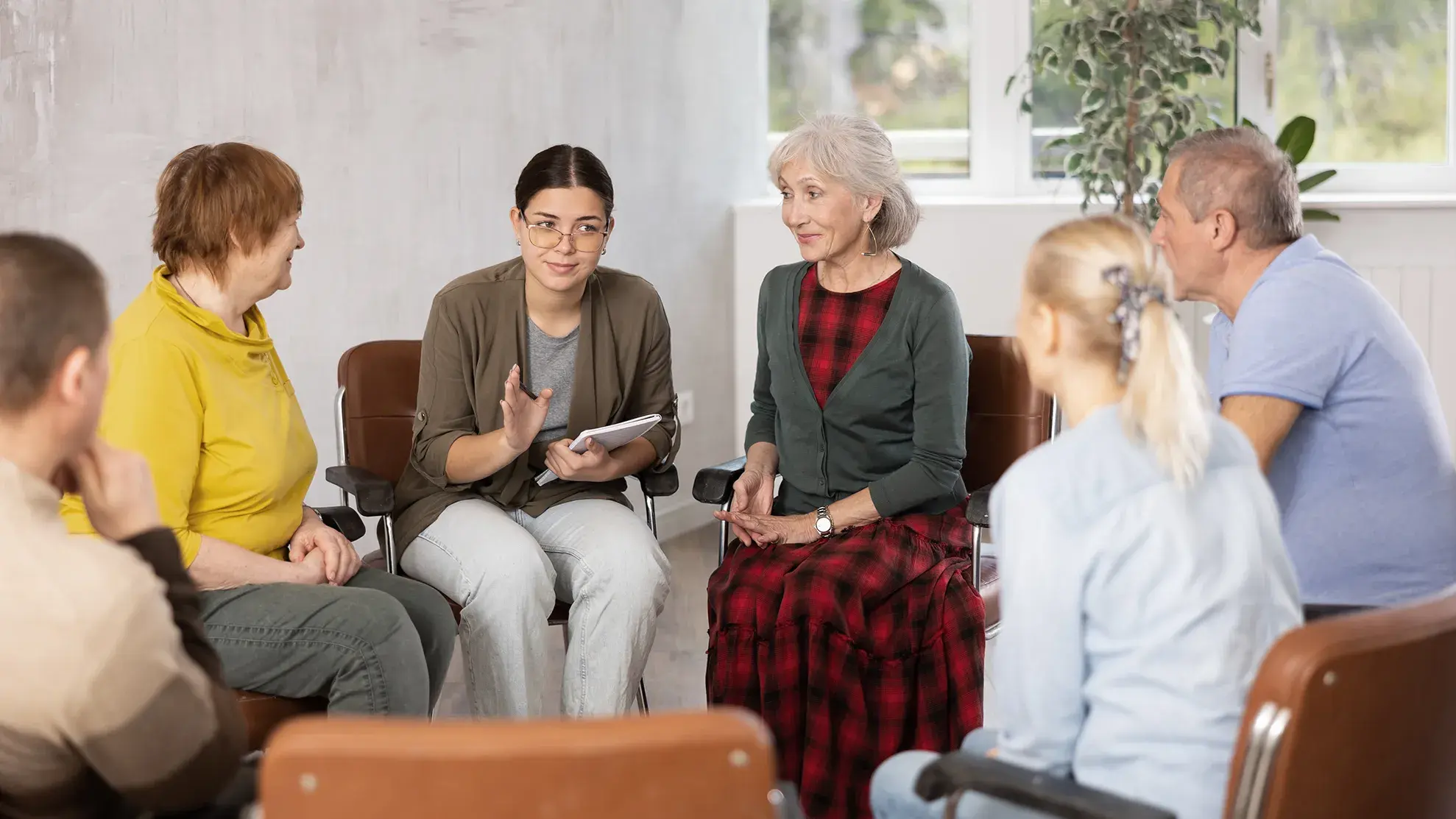 older adult group sitting in a circle on chairs listening to a facilitator