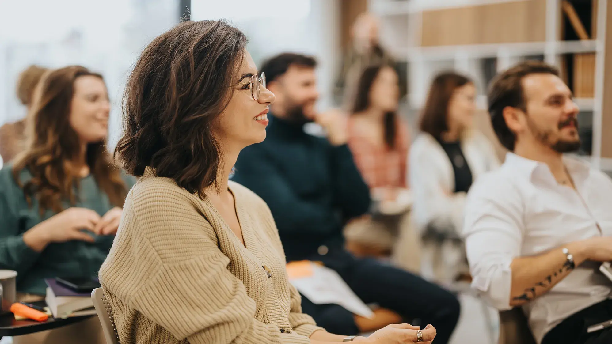 small group of young adults in a classroom setting paying attention to their facilitator