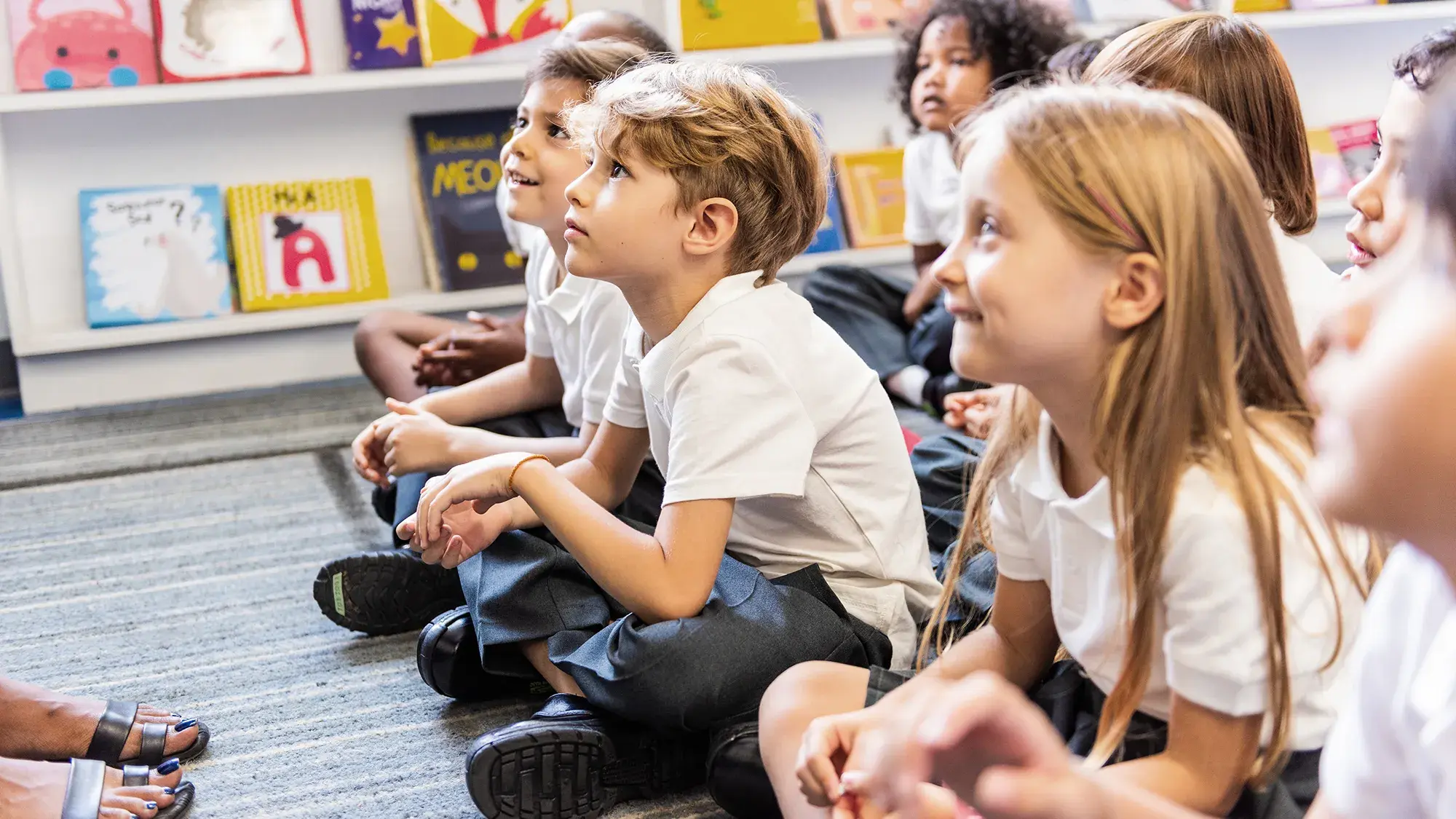 elementary school aged kids sitting crosslegged on the floor of a library