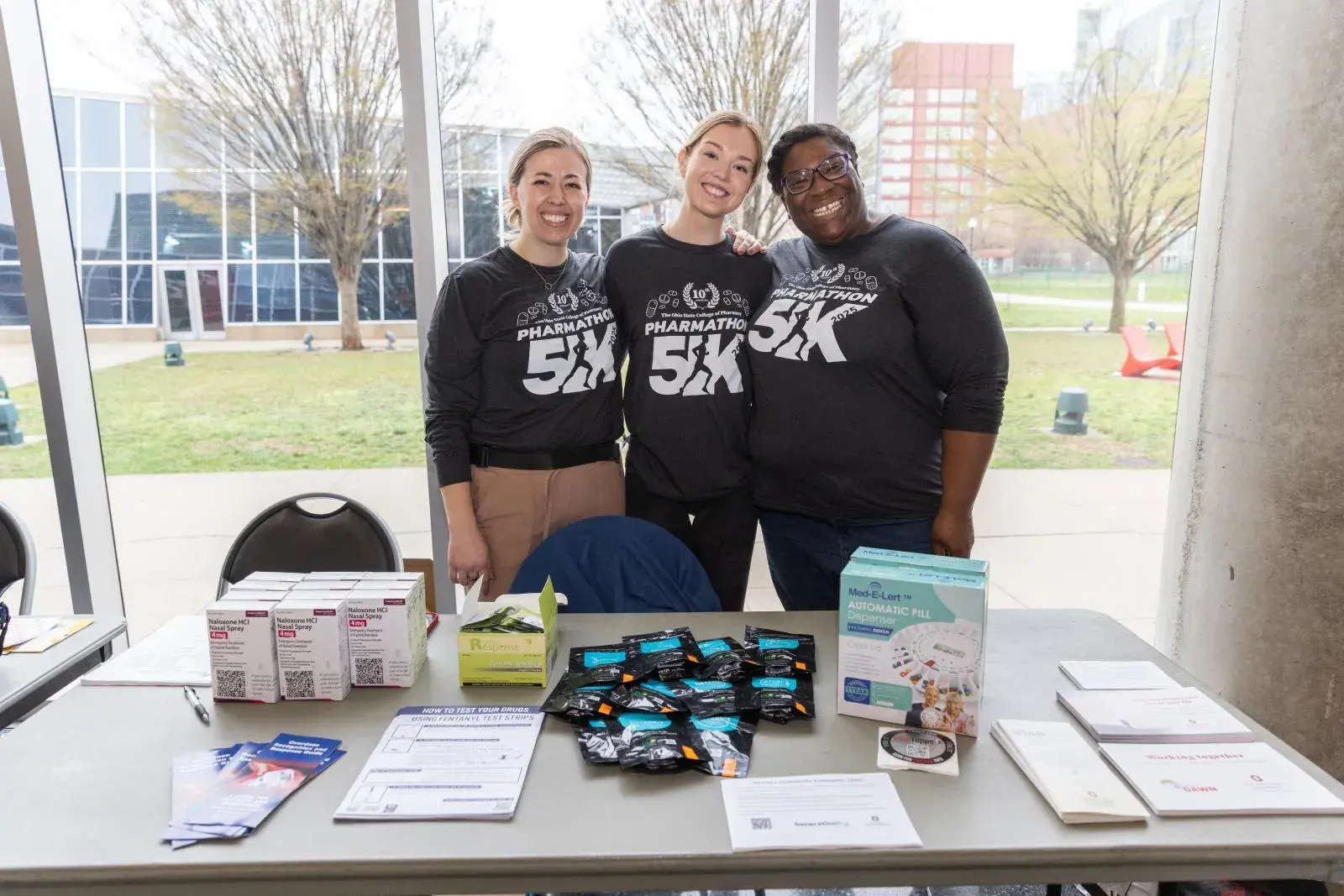 Kelsey Schmuhl stands with two other students at a table during a 5K event on Ohio State's campus.