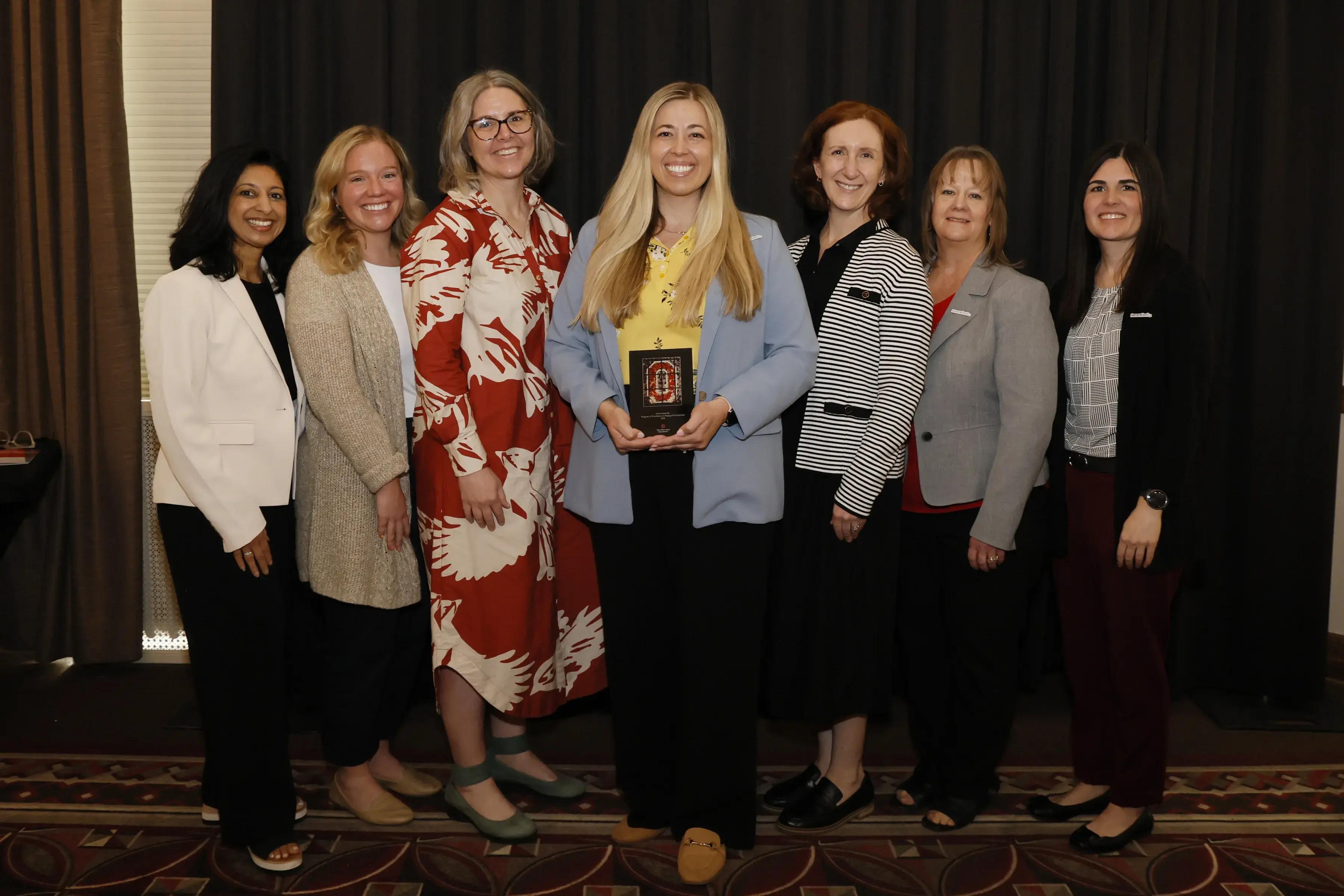 Members of Generation Rx and College of Pharmacy faculty pose together with the Program of Excellence plaque